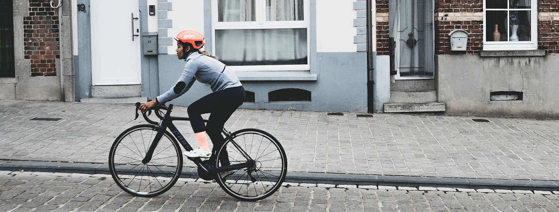 Woman cycling on a cobbled street by Coen Van de Broek from Unsplash
