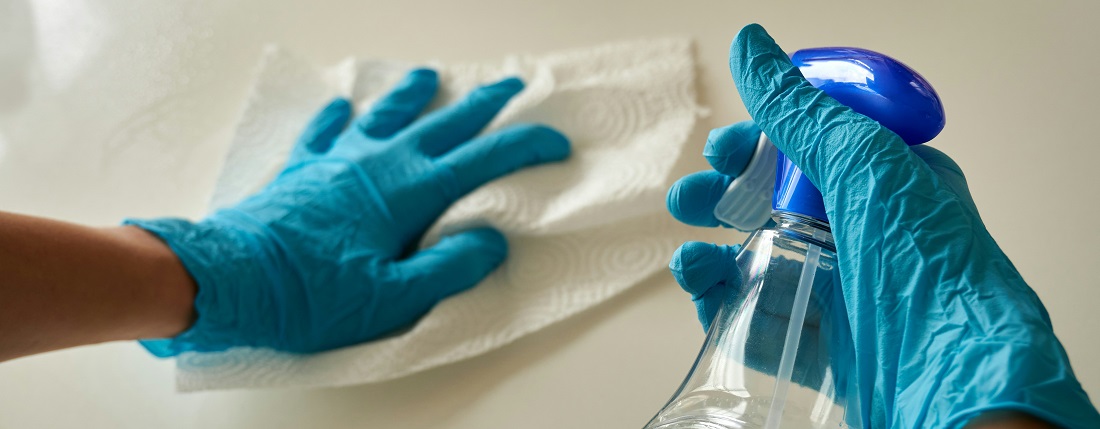 Person cleaning a countertop with blue gloves by Anton