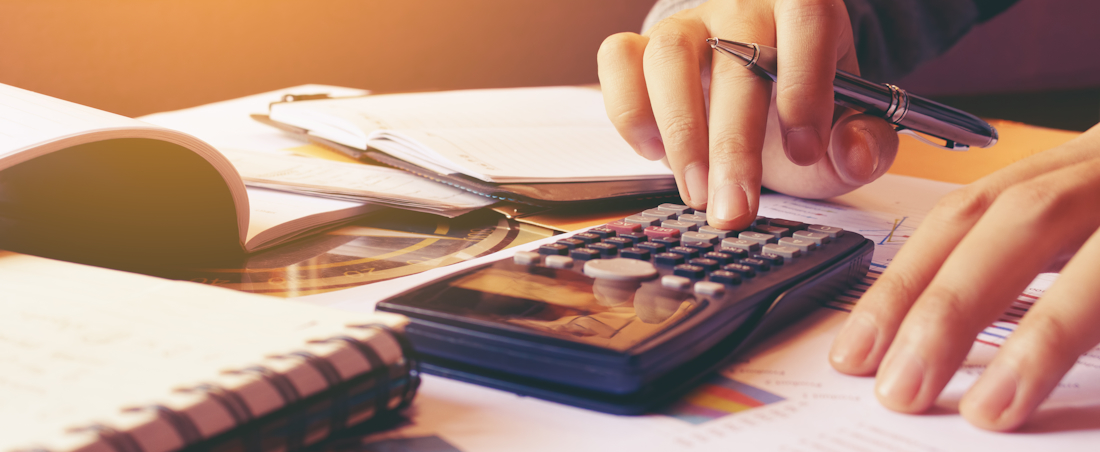 person using calculator next to opened notebooks