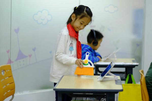 Student cleaning class table and using tablet